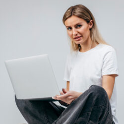 Modern Girl in white t-shirt with laptop in studio. Free creativity
